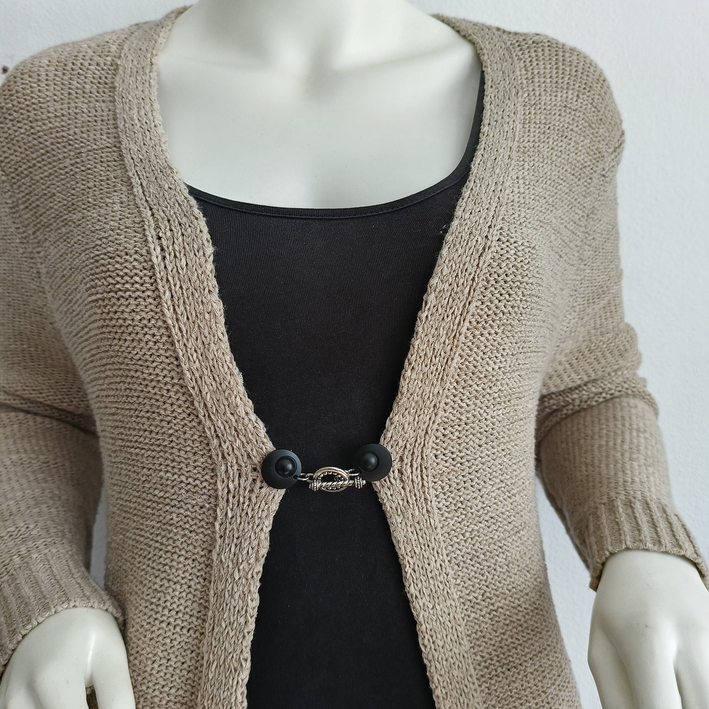 Vestsluiting met mat zwarte clips en een speelse zilverkleurige Circus-bedel, handgemaakt voor een elegante en unieke afwerking.