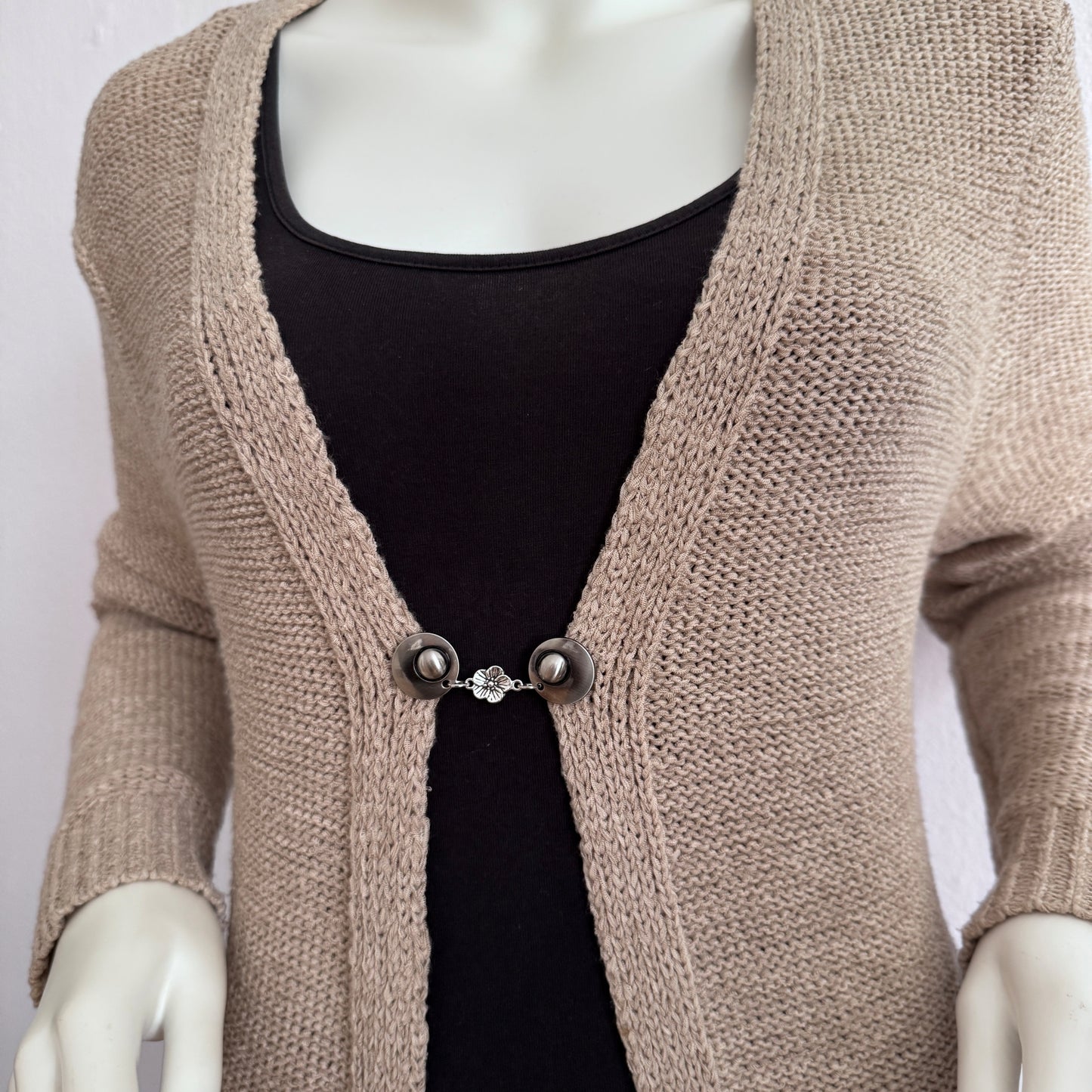 Vestsluiting Bloesem gedragen op een beige gebreid vest, elegante Fashionclip met zilverkleurige clips en verfijnde bloembedel.