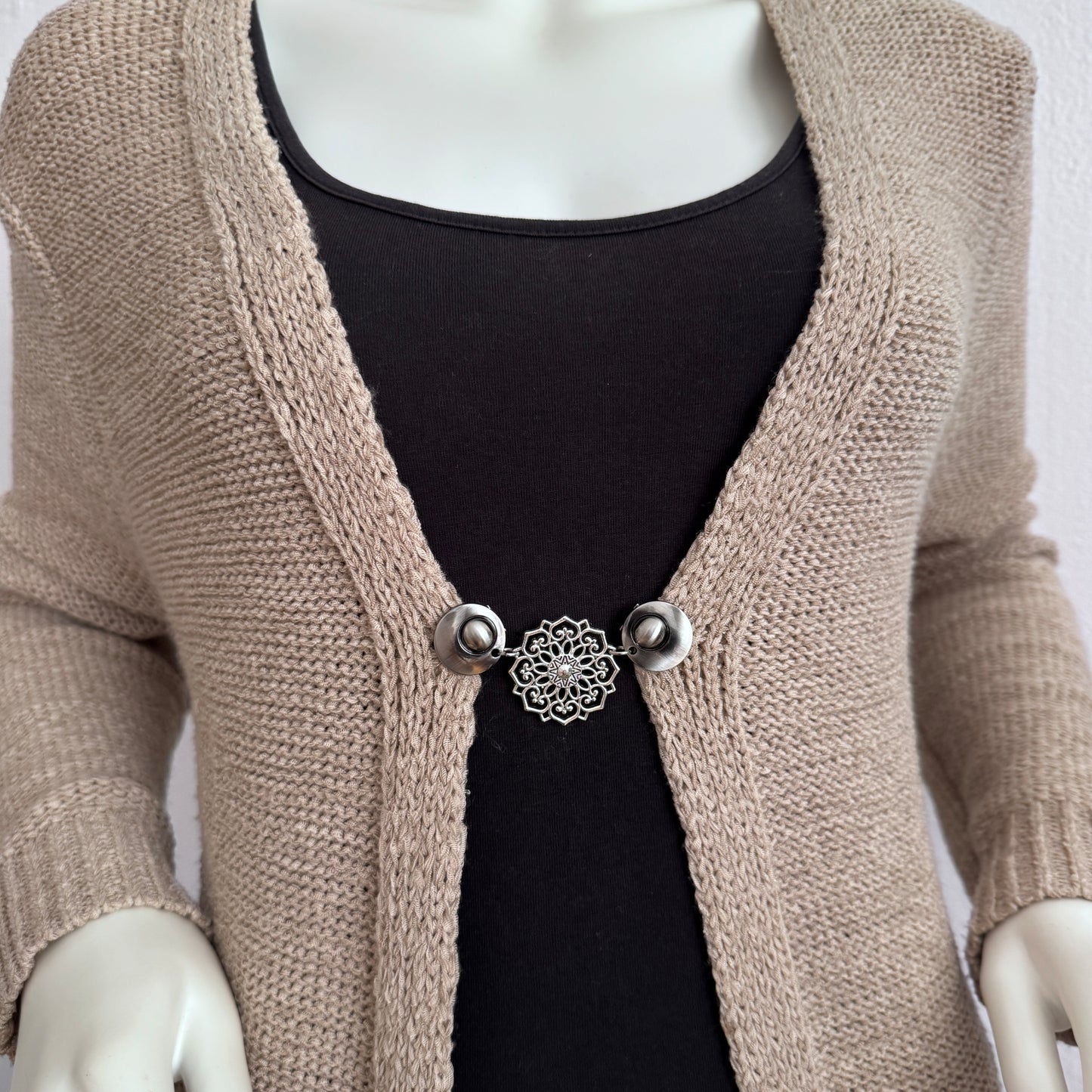Vestsluiting De Mandala gedragen op een beige gebreid vest, elegante Fashionclip met zilverkleurige clips en opengewerkte mandala tussenbedel.