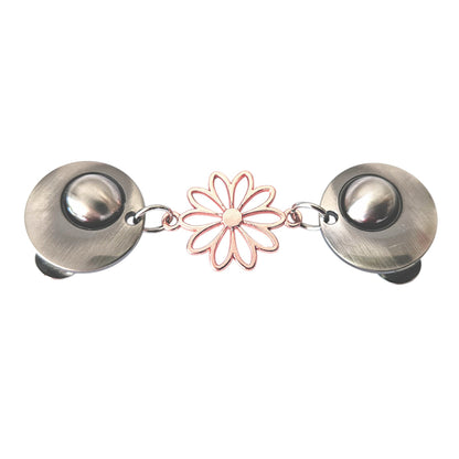 Vrolijke vestsluiting met zilverkleurige clips en een roségouden opengewerkte margriet, symbool voor frisheid en elegantie.