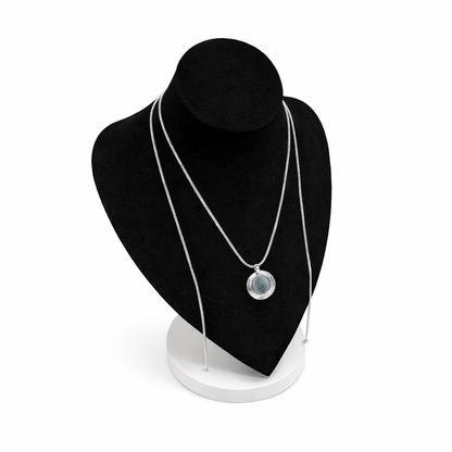 Zilverkleurige magneetketting getoond op zwart display, met ronde broche als voorbeeld bevestigd