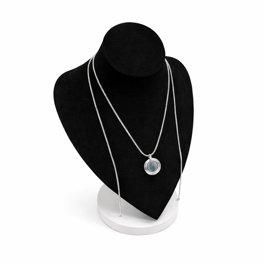 Zilverkleurige magneetketting getoond op zwart display, met ronde broche als voorbeeld bevestigd