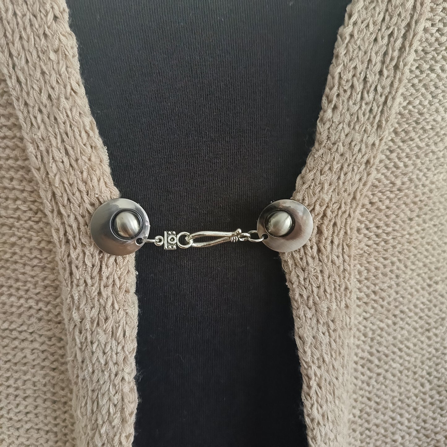 Zilverkleurige vestsluiting De Classic met haak-en-oogsluiting, rustig en tijdloos op een open gebreid vest.