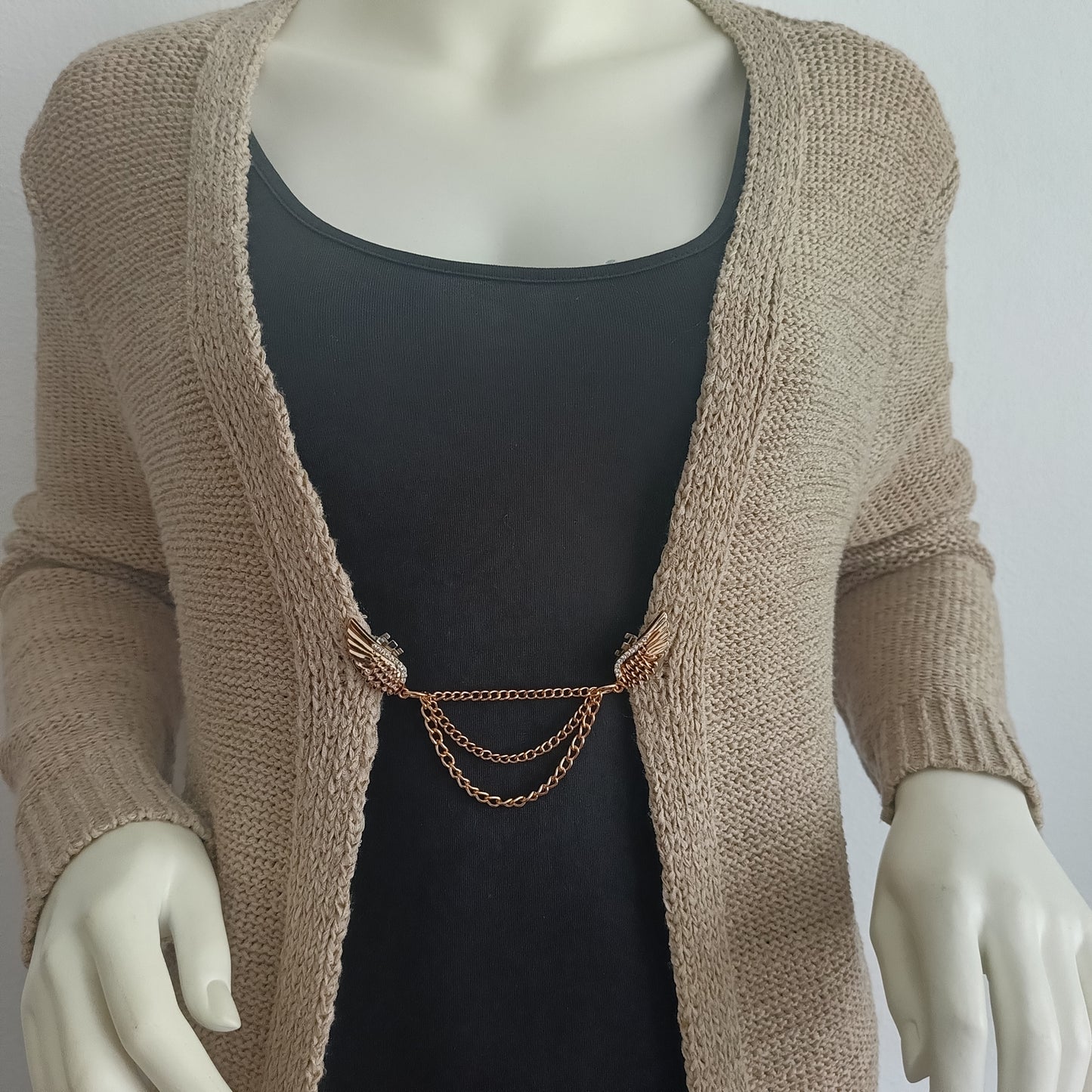 Goudkleurige vestsluiting met sierlijke vleugels en drie fijne kettingen, die kracht en elegantie combineren in een warm en stijlvol accent.