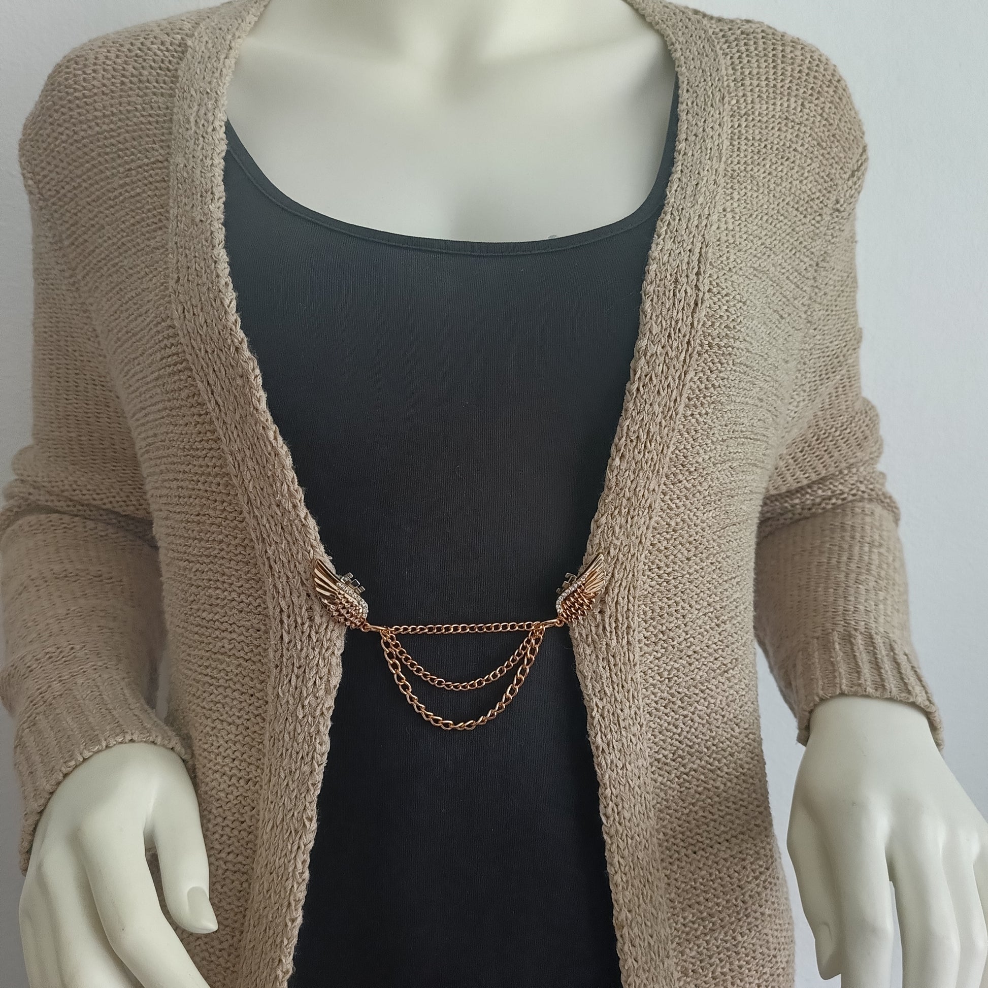 Goudkleurige vestsluiting met sierlijke vleugels en drie fijne kettingen, die kracht en elegantie combineren in een warm en stijlvol accent.