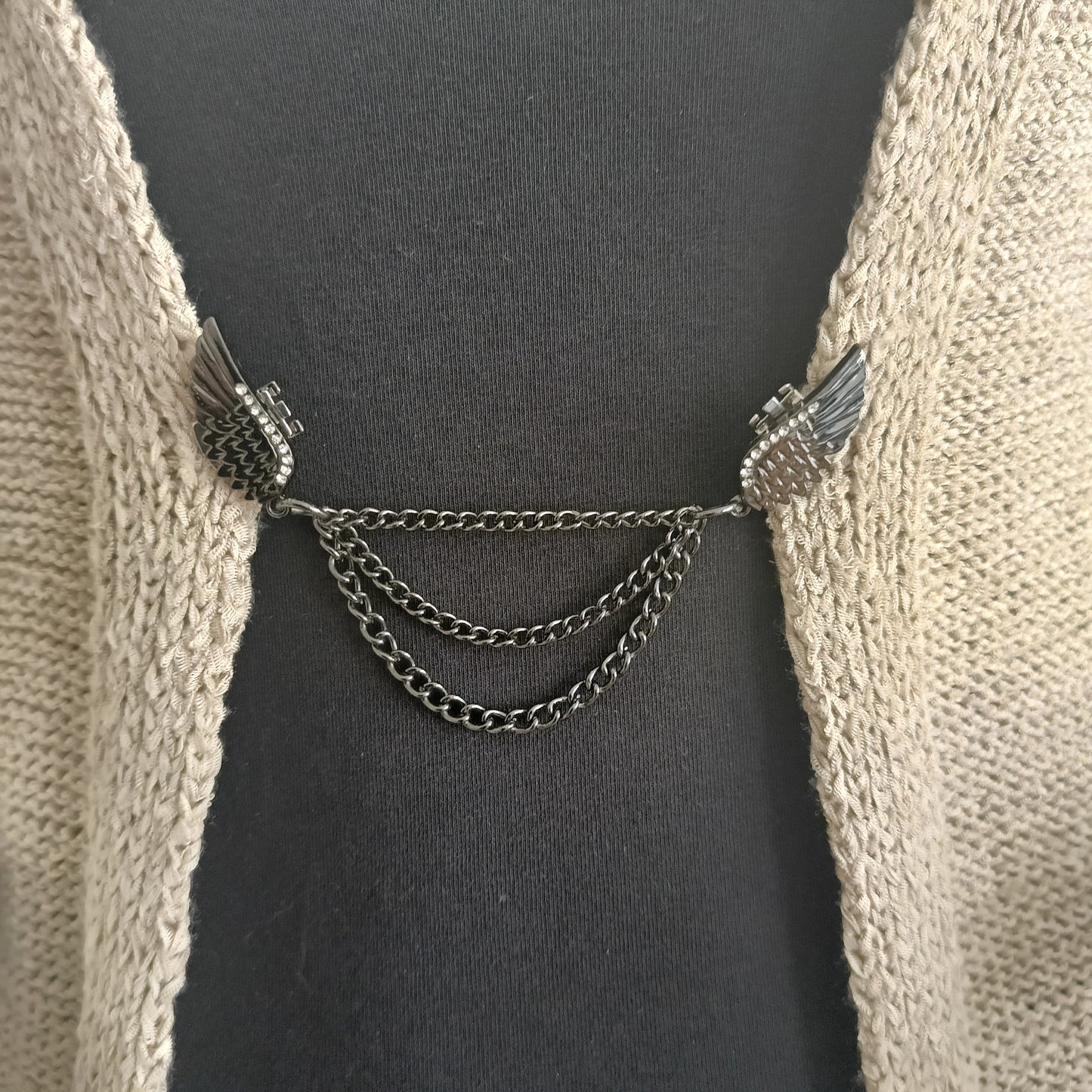 Zwartkleurige vestsluiting met sierlijke vleugels en drie fijne kettingen, handgemaakt voor een krachtige en elegante uitstraling.