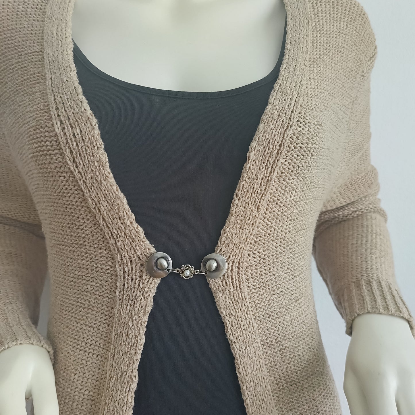 Handgemaakte vestsluiting De Kleine Parel in zilverkleur, met fijne ronde knopen en een subtiel pareldetail dat warmte en elegantie toevoegt aan ieder vest.