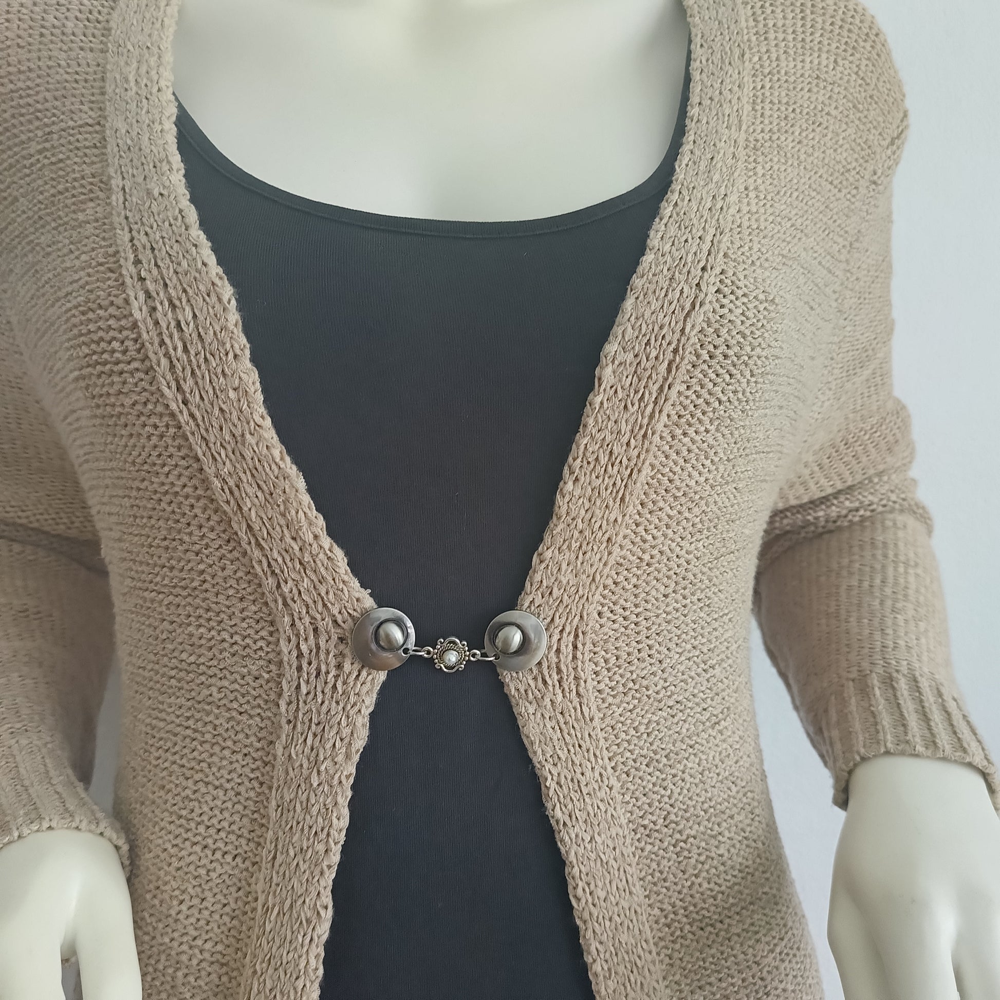 Handgemaakte vestsluiting De Kleine Parel in zilverkleur, met fijne ronde knopen en een subtiel pareldetail dat warmte en elegantie toevoegt aan ieder vest.