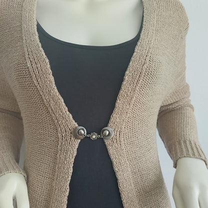 Handgemaakte vestsluiting De Kleine Parel in zilverkleur, met fijne ronde knopen en een subtiel pareldetail dat warmte en elegantie toevoegt aan ieder vest.