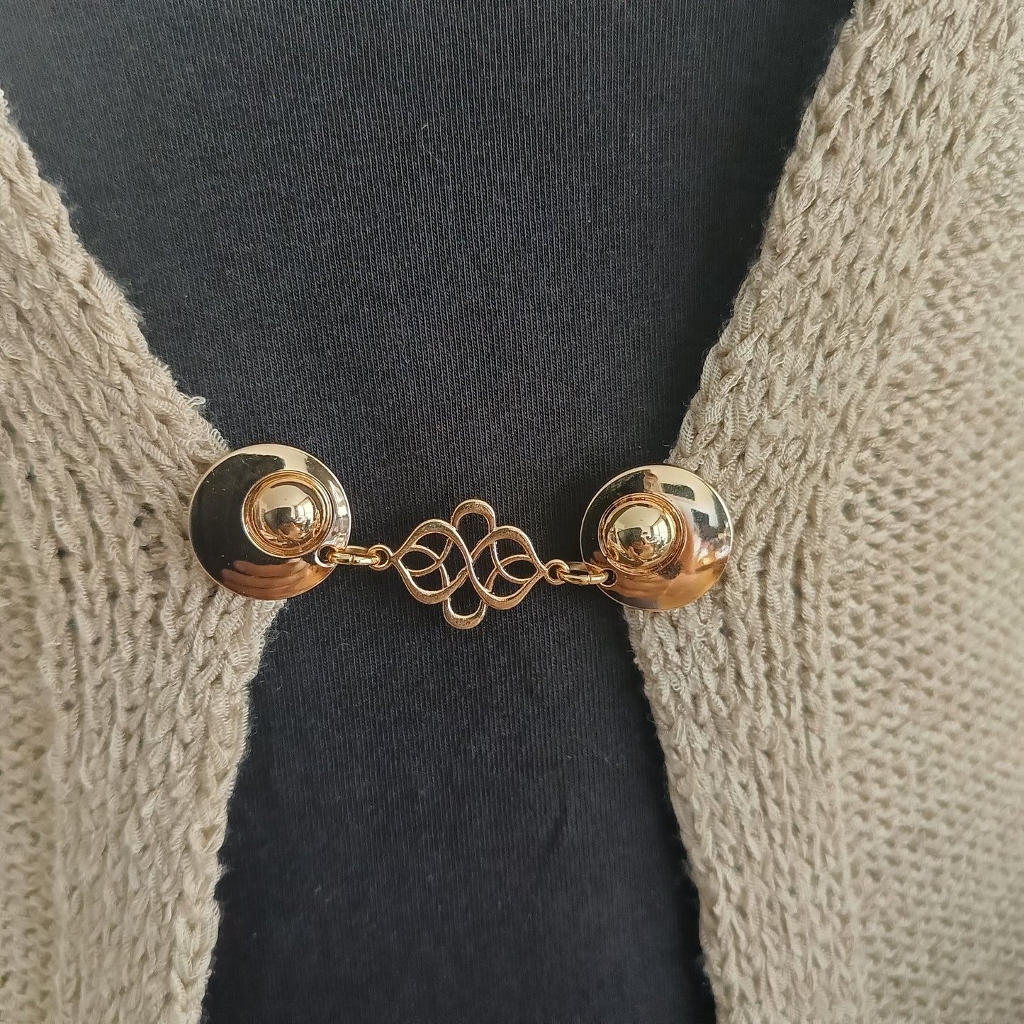 Deze gouden vestsluiting straalt verbondenheid en zachtheid uit. Een sierlijk symbool van evenwicht, met een warme glans.