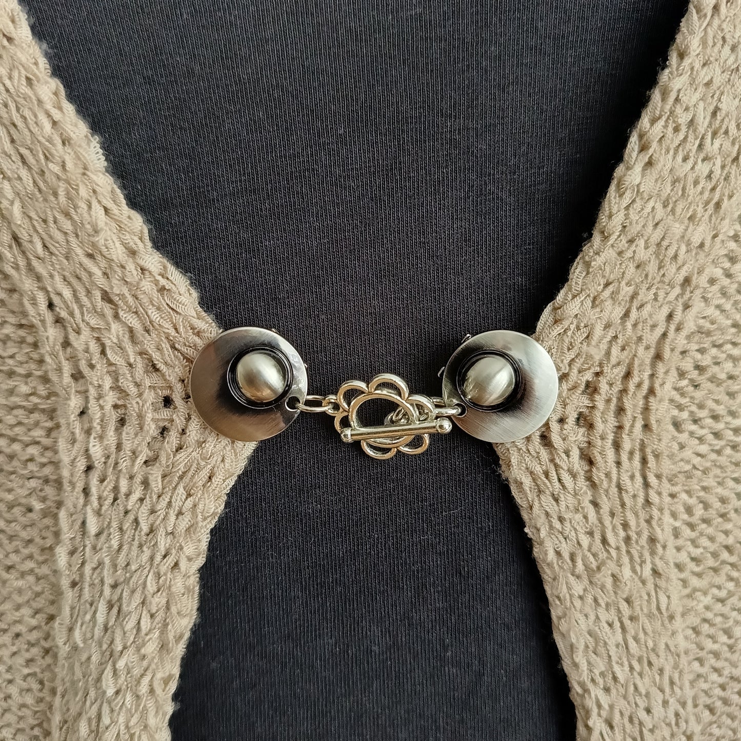 Zilverkleurige vestsluiting met een sierlijke bloemvormige bedel, handgemaakt voor een zachte en elegante uitstraling.