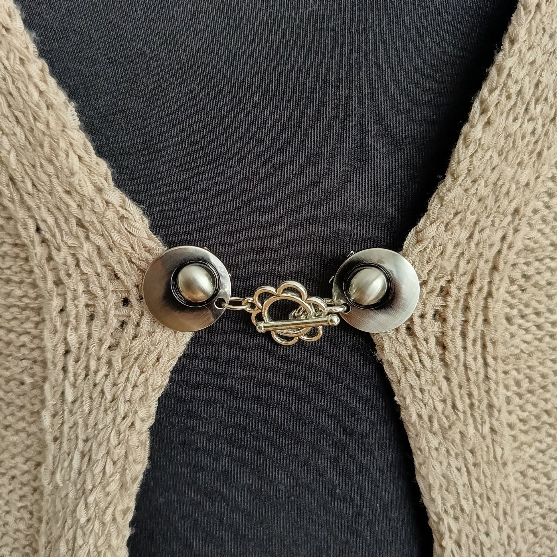 Zilverkleurige vestsluiting met een sierlijke bloemvormige bedel, handgemaakt voor een zachte en elegante uitstraling.