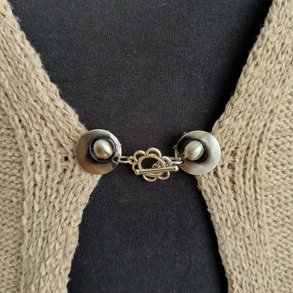 Zilverkleurige vestsluiting met een sierlijke bloemvormige bedel, handgemaakt voor een zachte en elegante uitstraling.