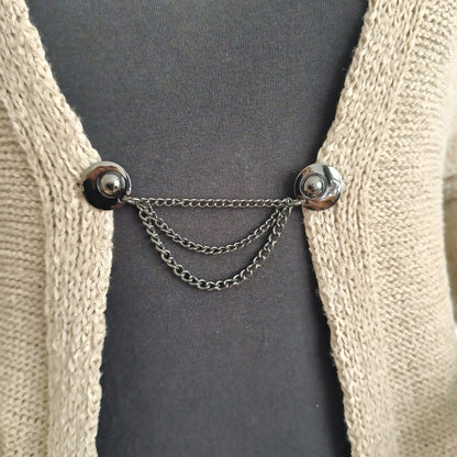 Mat zwarte vestsluiting met drie fijne kettingen, handgemaakt voor een stoere en stijlvolle uitstraling.