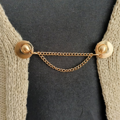 Goudkleurige vestsluiting met twee verfijnde kettingen, handgemaakt voor een stijlvolle en chique uitstraling.