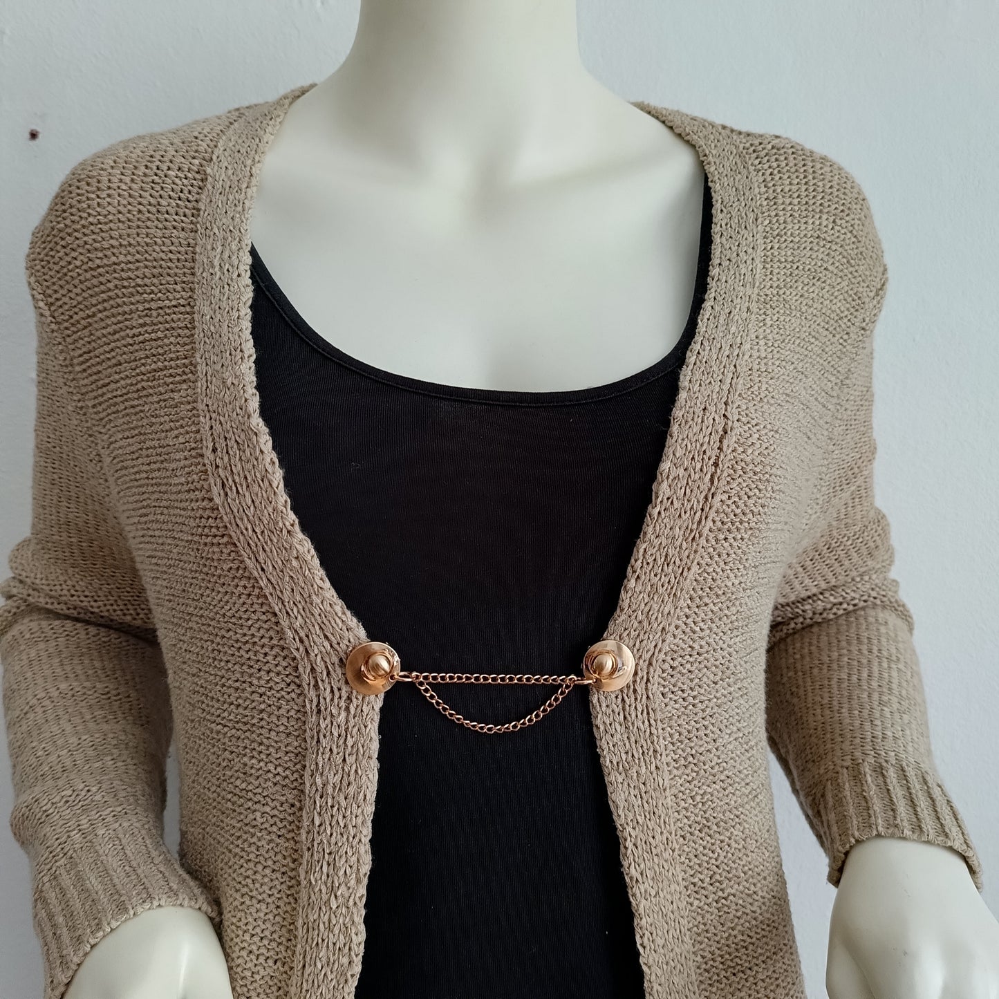 Goudkleurige vestsluiting met twee fijne kettingen voor een elegante en subtiele afwerking van elke outfit.