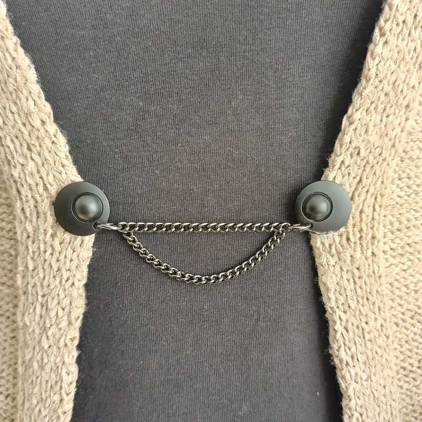 Mat zwarte vestsluiting met twee verfijnde kettingen, handgemaakt voor een moderne en stijlvolle uitstraling.