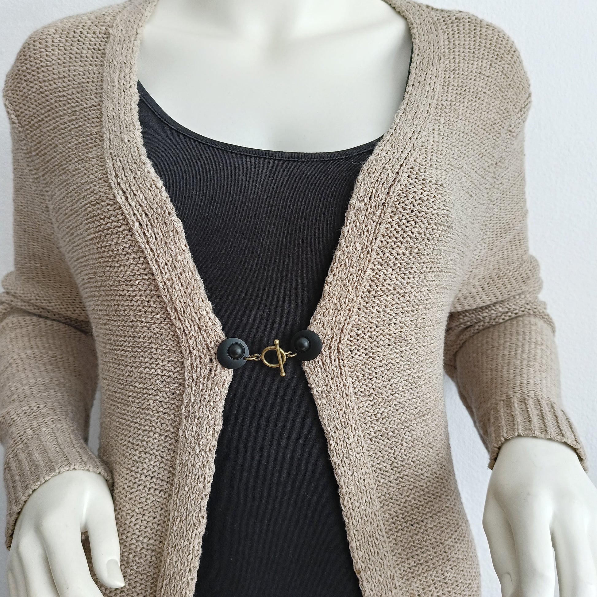 Vestsluiting met mat zwarte clips en een warme bronzen T-Bar, handgemaakt voor een krachtige en moderne afwerking.