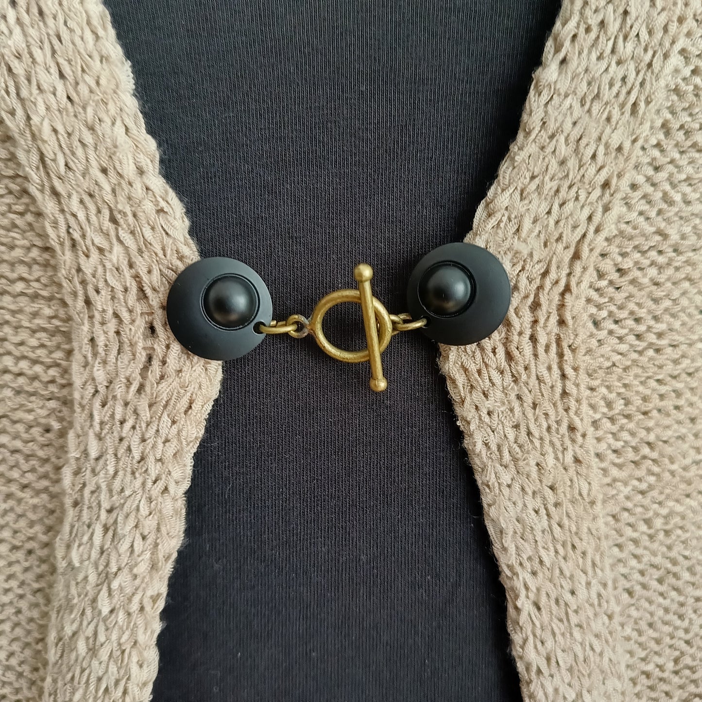 Vestsluiting met mat zwarte clips en een bronzen T-Bar, handgemaakt voor een krachtige en stijlvolle uitstraling.