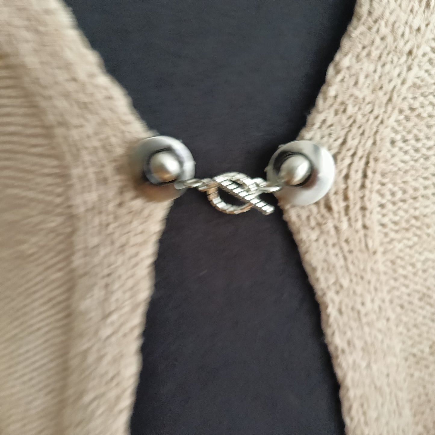 Close-up van een zilverkleurige T-Bar vestsluiting met een verfijnde touwring-bedel, handgemaakt voor een elegante en tijdloze uitstraling.