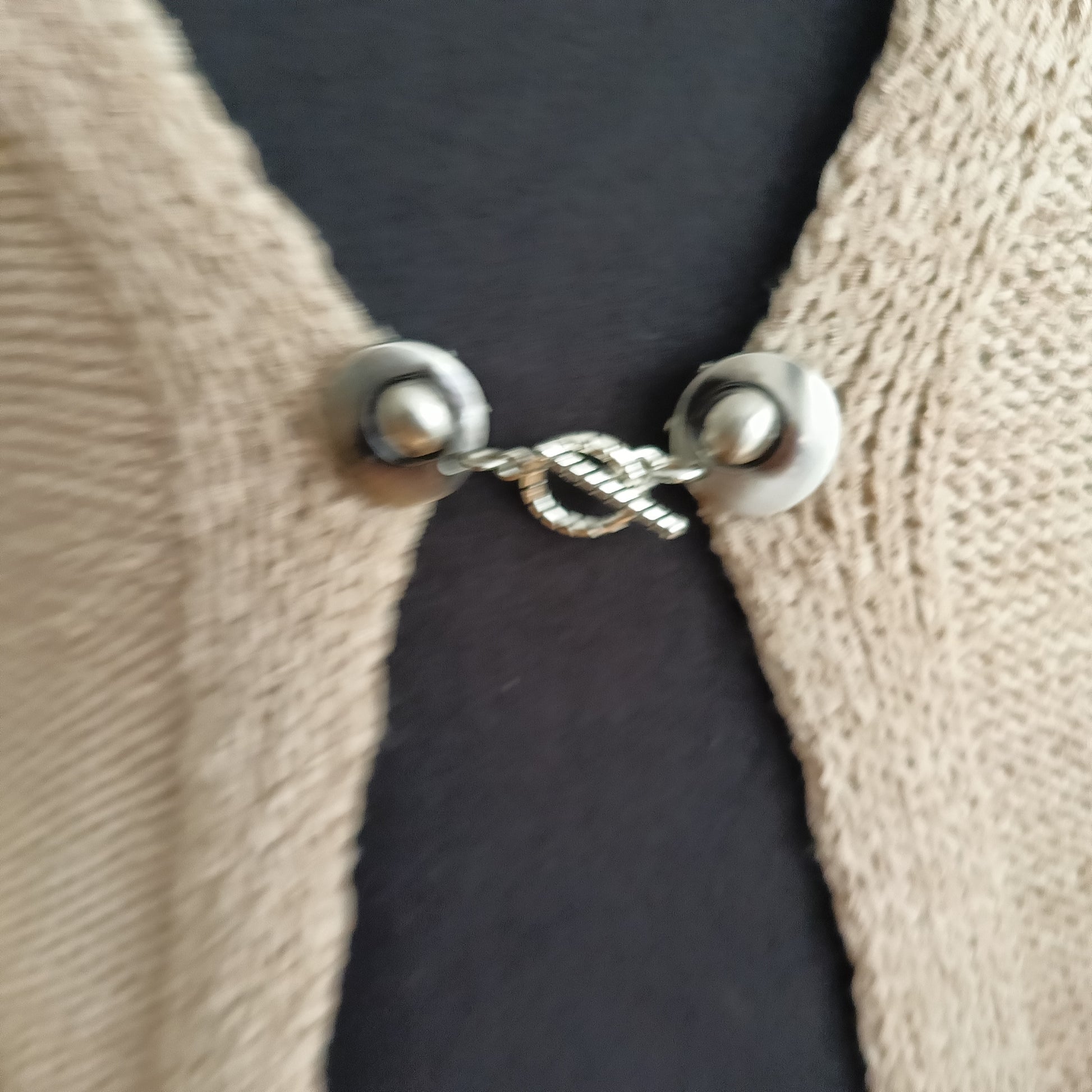 Close-up van een zilverkleurige T-Bar vestsluiting met een verfijnde touwring-bedel, handgemaakt voor een elegante en tijdloze uitstraling.