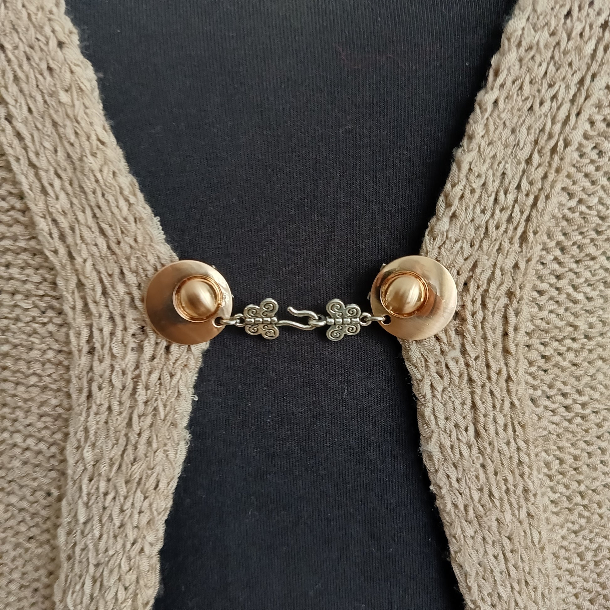 Goudkleurige haak-en-oog vestsluiting met verfijnde vlinderdetails, handgemaakt voor een elegante en sierlijke uitstraling.