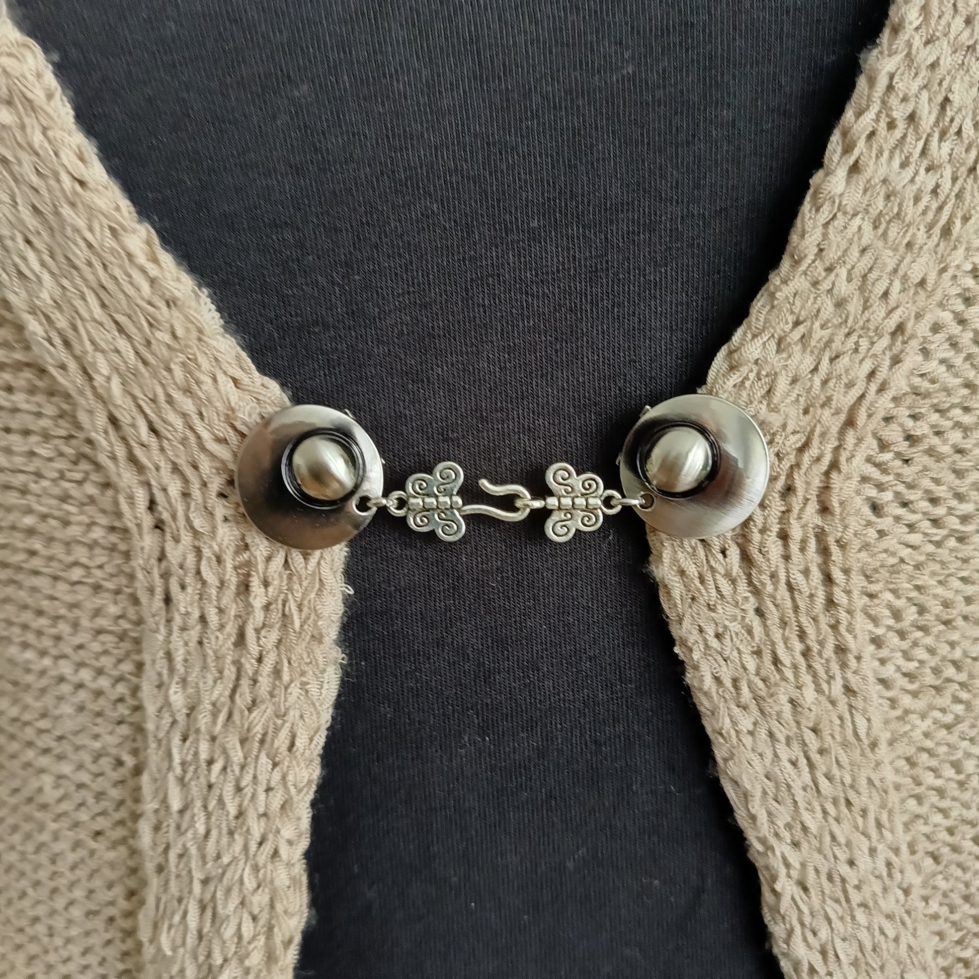 Zilverkleurige haak-en-oog vestsluiting met sierlijke vlinderdetails, handgemaakt voor een elegante en verfijnde uitstraling.