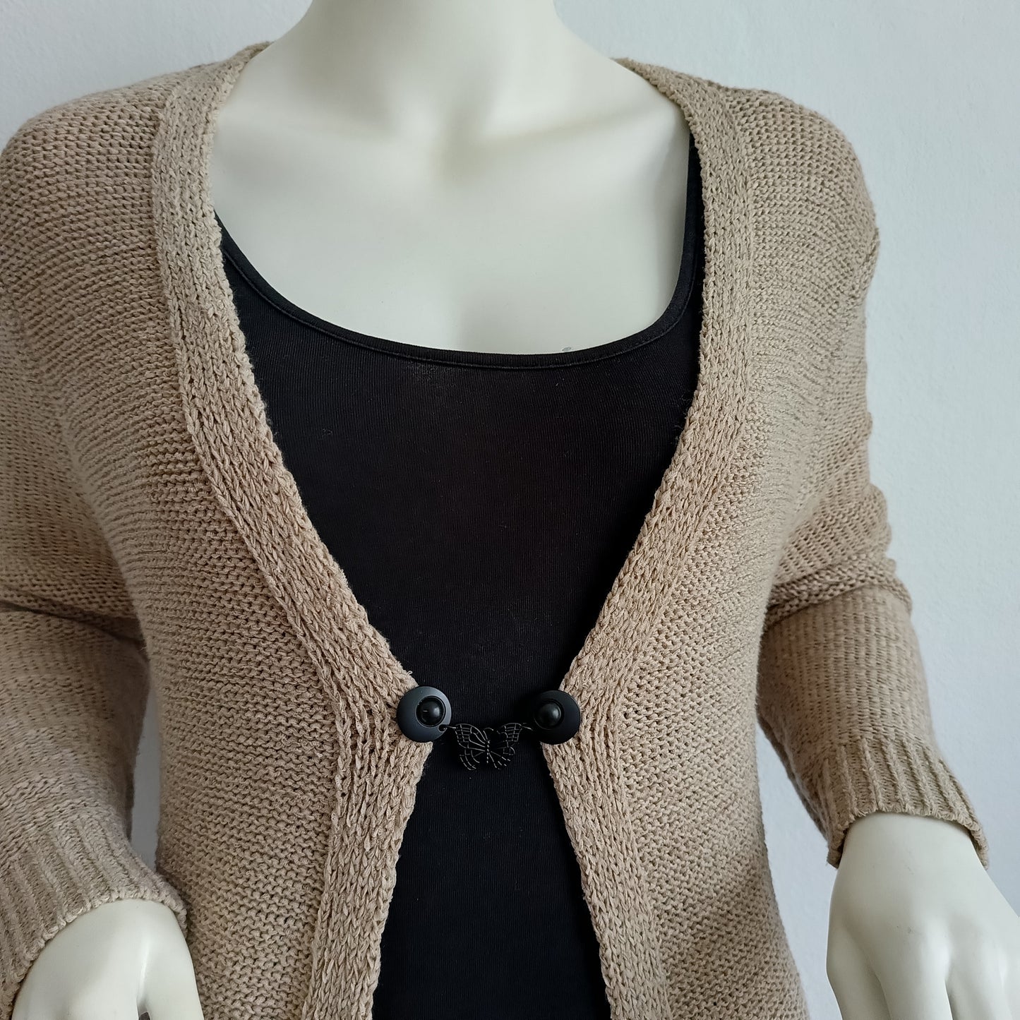 Handgemaakte vestsluiting met een subtiele zwarte vlinder, die elegantie en verfijning toevoegt aan elke outfit.