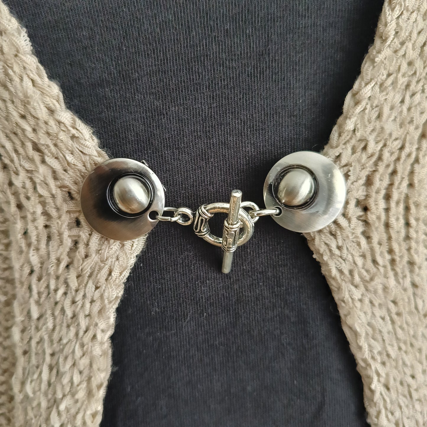 Zilverkleurige vestsluiting met een stijlvolle evenwichtsbedel, handgemaakt voor een harmonieuze en elegante afwerking.