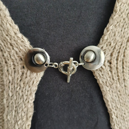 Zilverkleurige vestsluiting met een stijlvolle evenwichtsbedel, handgemaakt voor een harmonieuze en elegante afwerking.