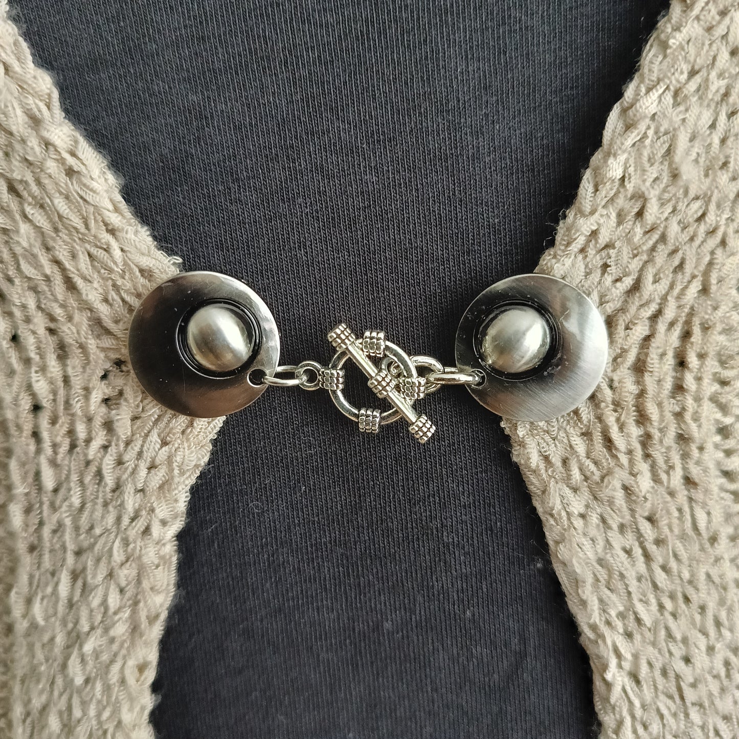 Zilverkleurige vestsluiting met een gedetailleerde structuurbedel, handgemaakt voor een krachtige en stijlvolle uitstraling.