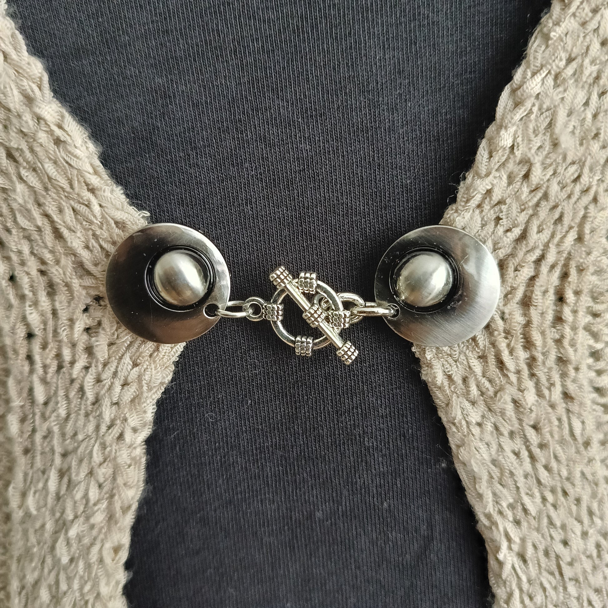 Zilverkleurige vestsluiting met een gedetailleerde structuurbedel, handgemaakt voor een krachtige en stijlvolle uitstraling.