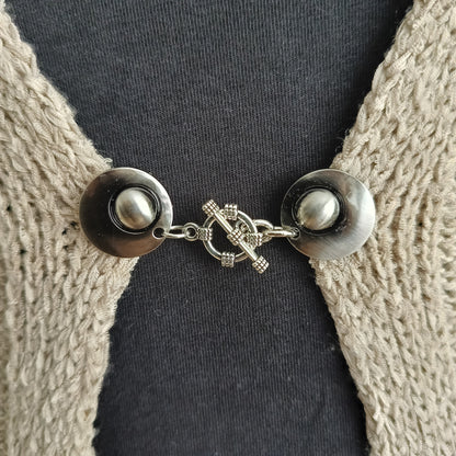 Zilverkleurige vestsluiting met een gedetailleerde structuurbedel, handgemaakt voor een krachtige en stijlvolle uitstraling.