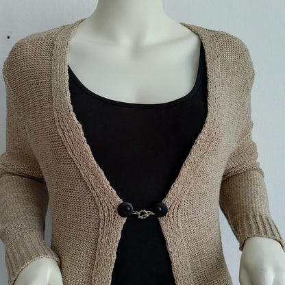 Vestsluiting met mat zwarte clips en een zilverkleurige structuurbedel, handgemaakt voor een krachtige en stijlvolle uitstraling.