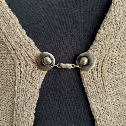 “Zilverkleurige vestsluiting met verfijnde wikkelvorm, handgemaakt en stevig bevestigd op een vest.”