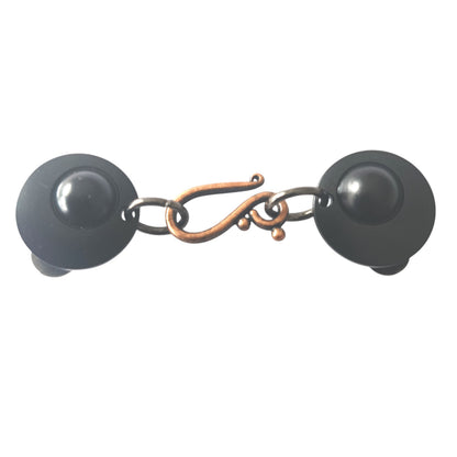 Losse vestsluiting met mat zwarte clips en een koperkleurige haak-en-oog sluiting, handgemaakt voor een stijlvolle en warme uitstraling.