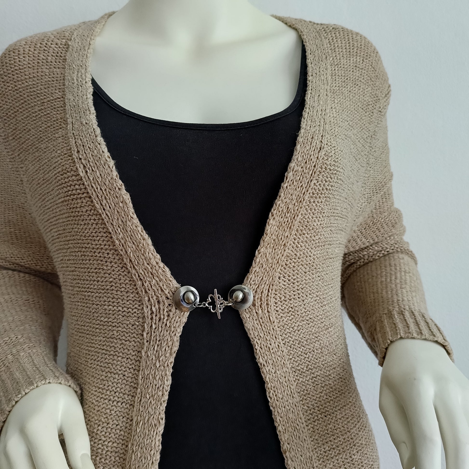 Zilverkleurige handgemaakte vestclip met een sierlijk halo-ornament, bevestigd aan twee ronde Fashionclip-knoppen.