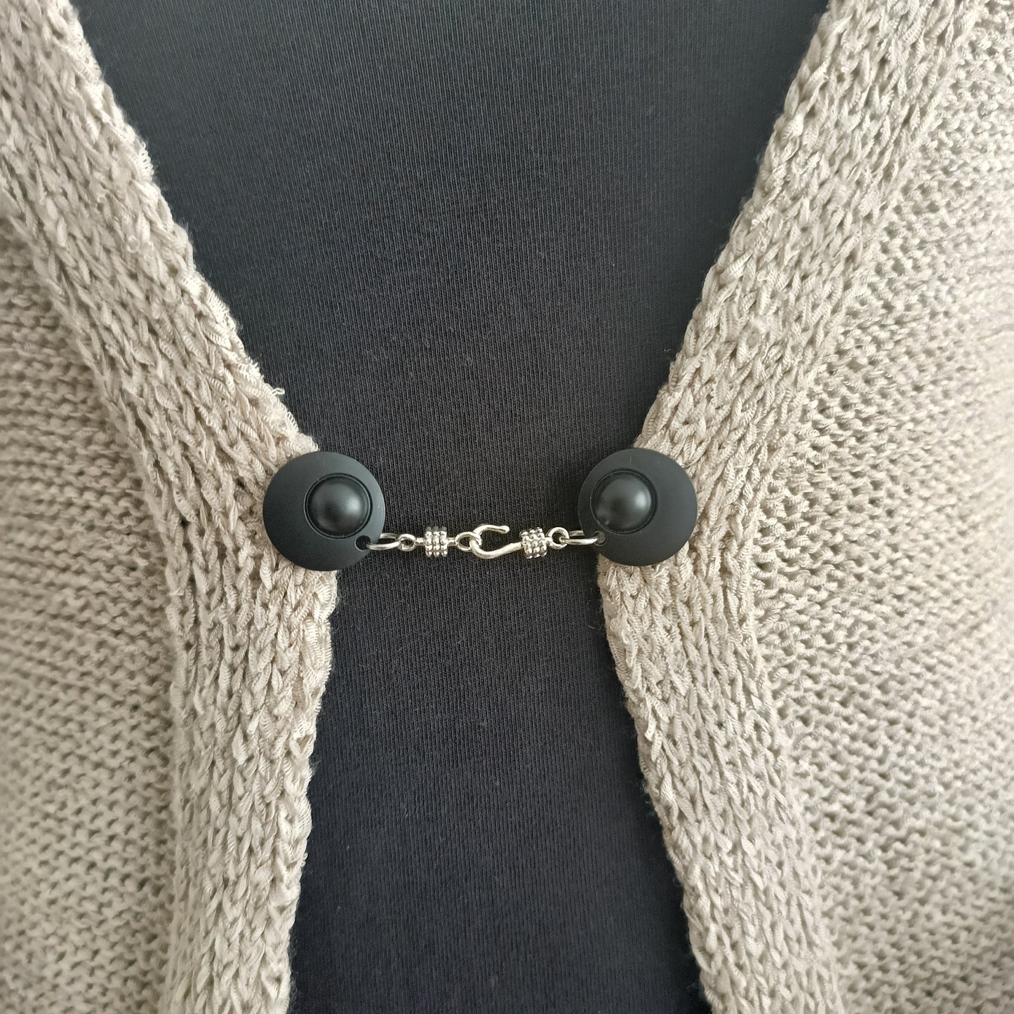 Mat zwarte vestsluiting met zilverkleurige haaksluiting, stoer en stijlvol als subtiel accent op een open vest.