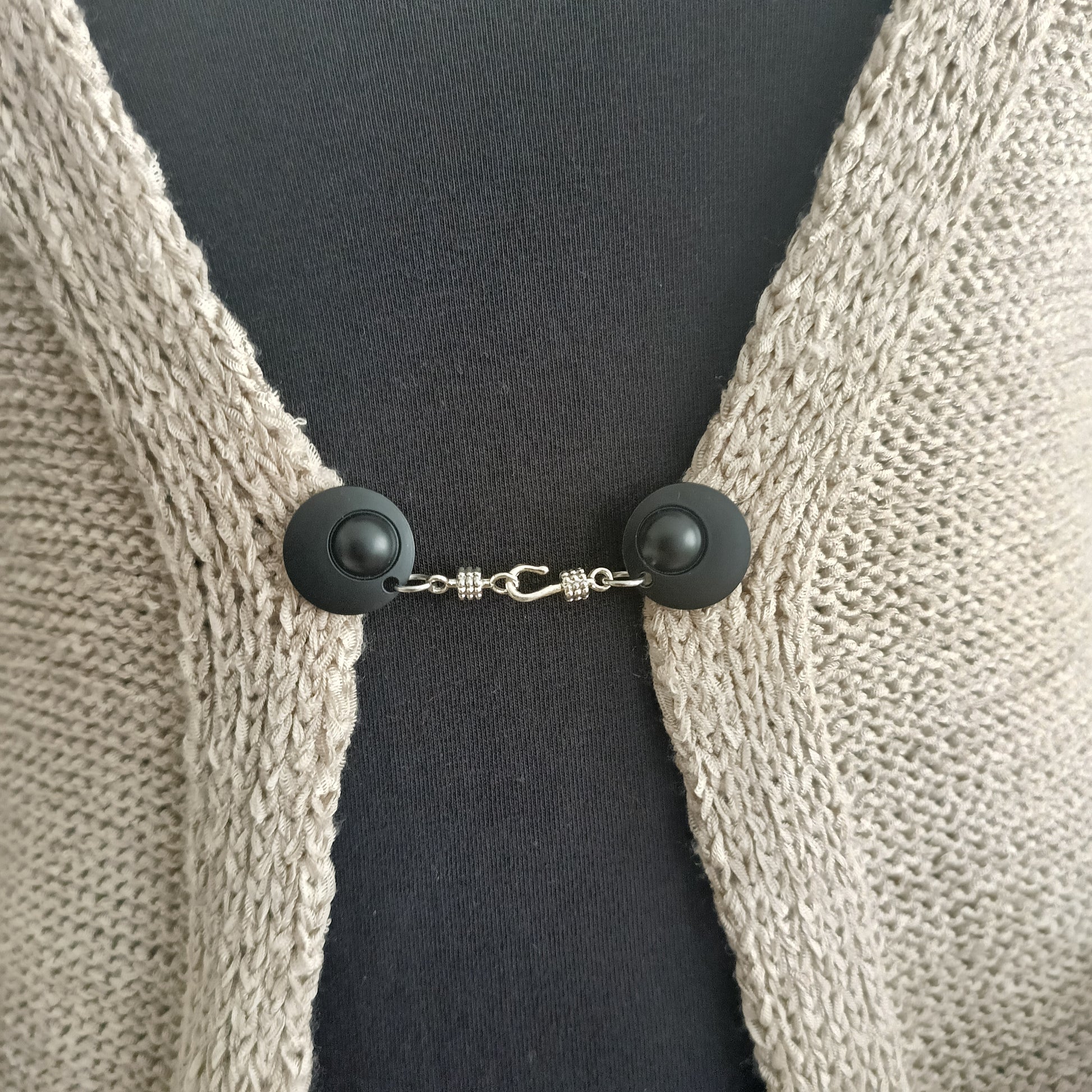 Mat zwarte vestsluiting met zilverkleurige haaksluiting, stoer en stijlvol als subtiel accent op een open vest.