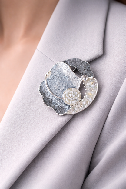 Abstracte zilverkleurige magneetbroche met ronde vormen en mozaïekstructuur in zachte grijstinten