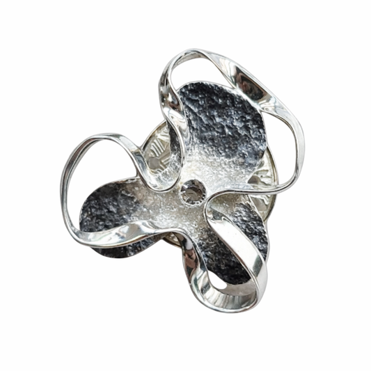 Abstracte zilverkleurige magneetbroche met open rozetvorm en een speelse, golvende structuur.