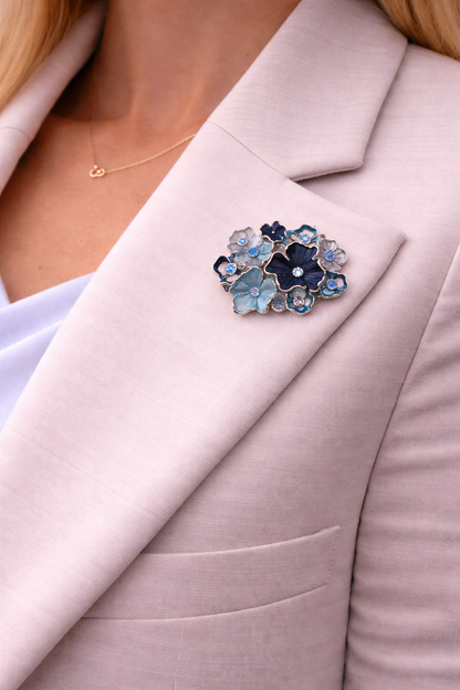 Magneetbroche Blauwe Bloemenpracht gedragen op lichtroze blazer, verfijnde bloemen in blauwtinten met elegante uitstraling