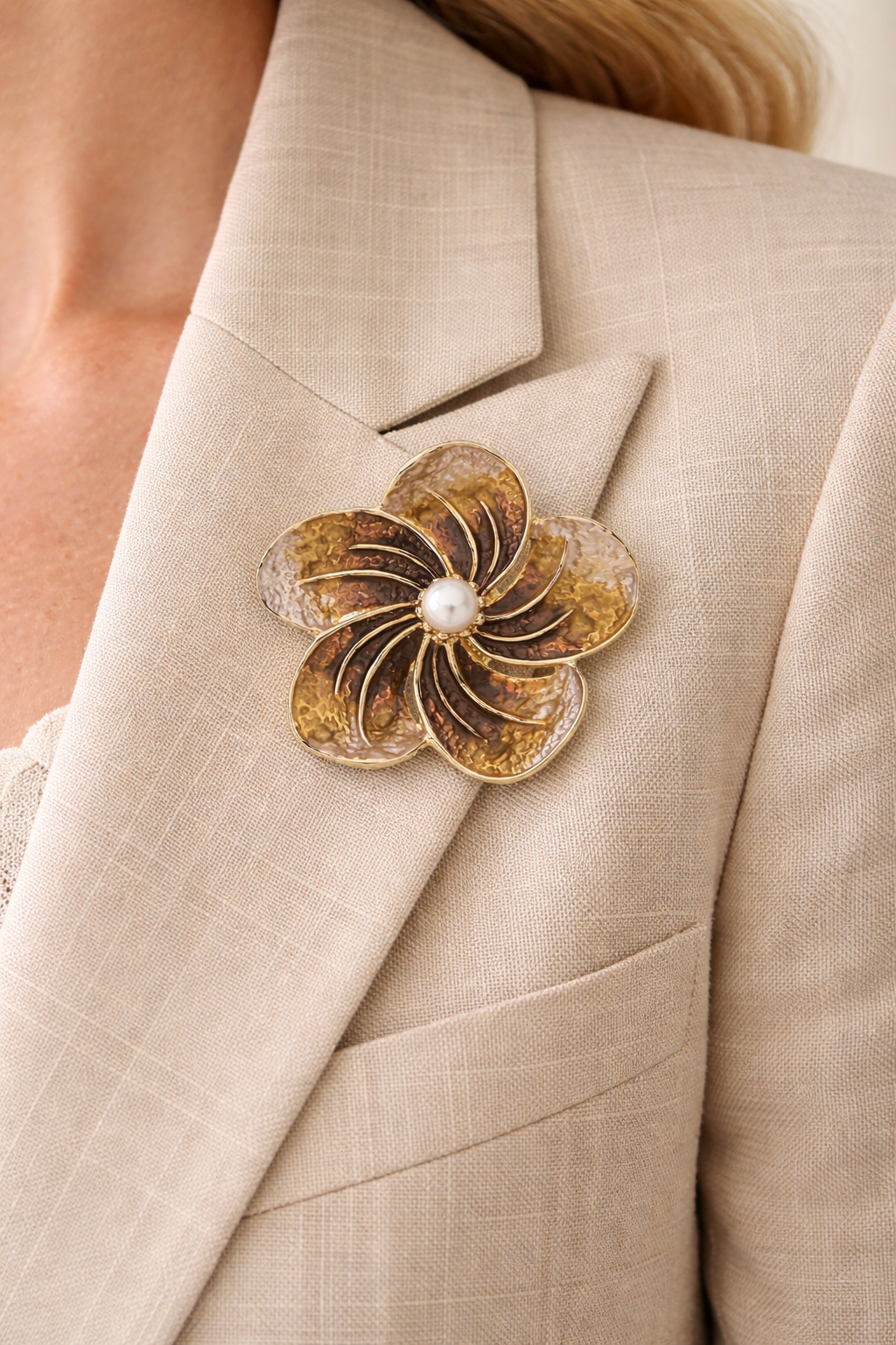 Magneetbroche Gouden Parelbloem gedragen op een colbert, elegante bloem met parel en warme goudtinten zonder gaatjes in de stof