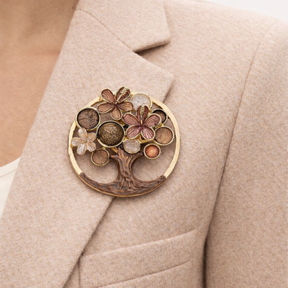 “Magneetbroche Levensboom bruin gedragen op een beige colbert, warme aardetinten met boom en bloemdetails in een ronde omlijsting.”