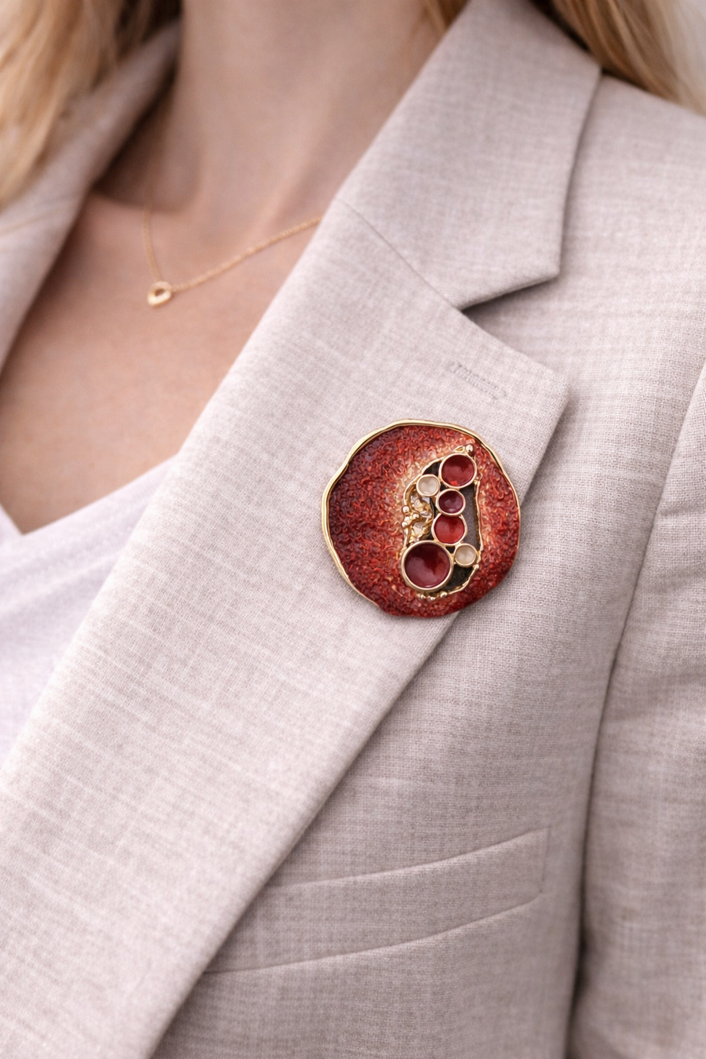 Magneetbroche Nr.19 Robijn Pracht gedragen op een licht colbert, elegante damesbroche met robijnrode tinten en goudkleurige details.