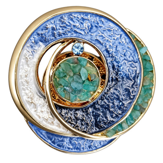Ronde magneetbroche met blauwe en witte tinten, goudkleurige cirkels en turquoise steentjes. Deze stijlvolle broche zonder speld straalt rust, balans en elegantie uit en vormt een opvallende blikvanger op ieder jasje.