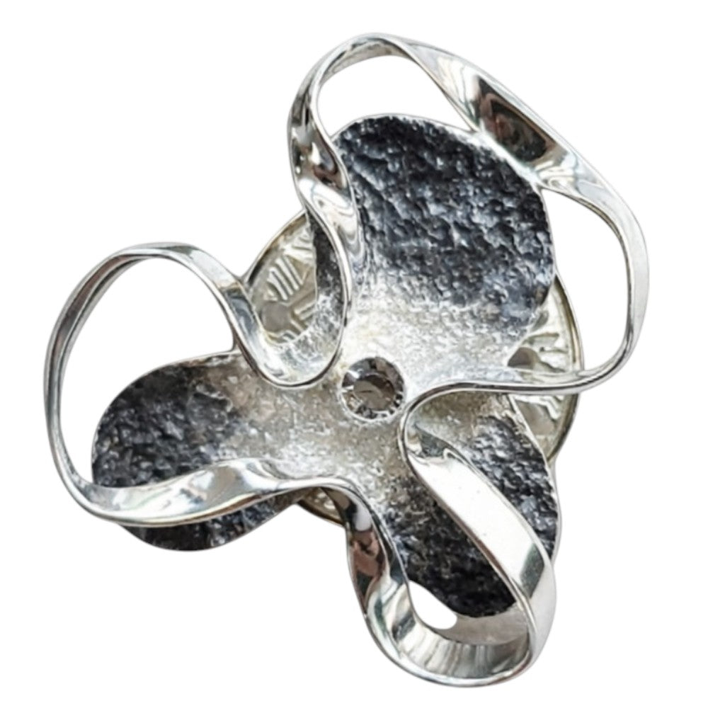Abstracte zilverkleurige magneetbroche met sierlijke organische vormen, donkere accenten en een subtiele strasssteen in het midden. Een moderne broche zonder speld voor een stijlvolle en eigentijdse uitstraling.