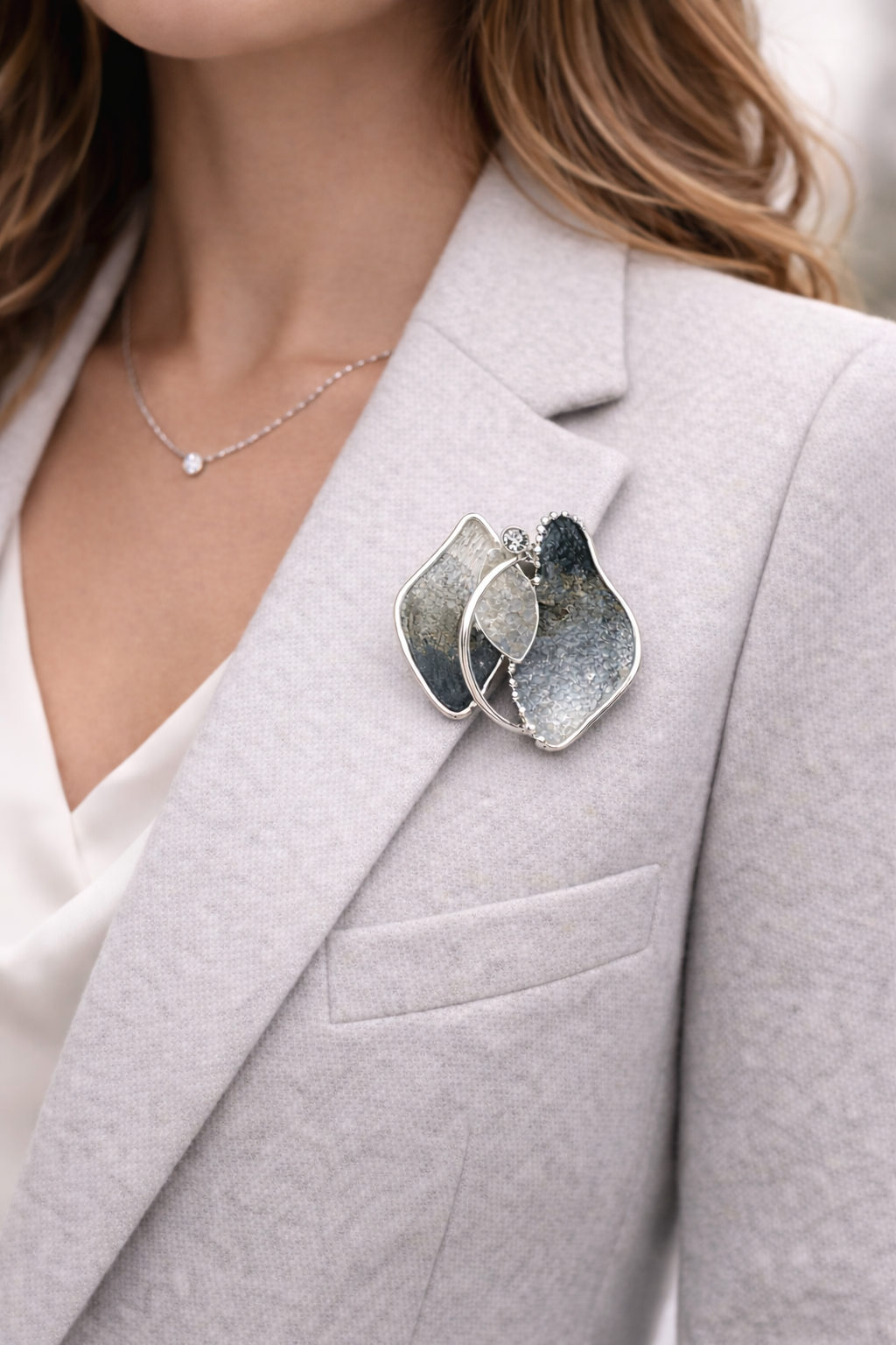Magneetbroche Nr.36 Zilver in Evenwicht gedragen op een licht colbert, elegante damesbroche met zilverkleurige vormen en moderne uitstraling.