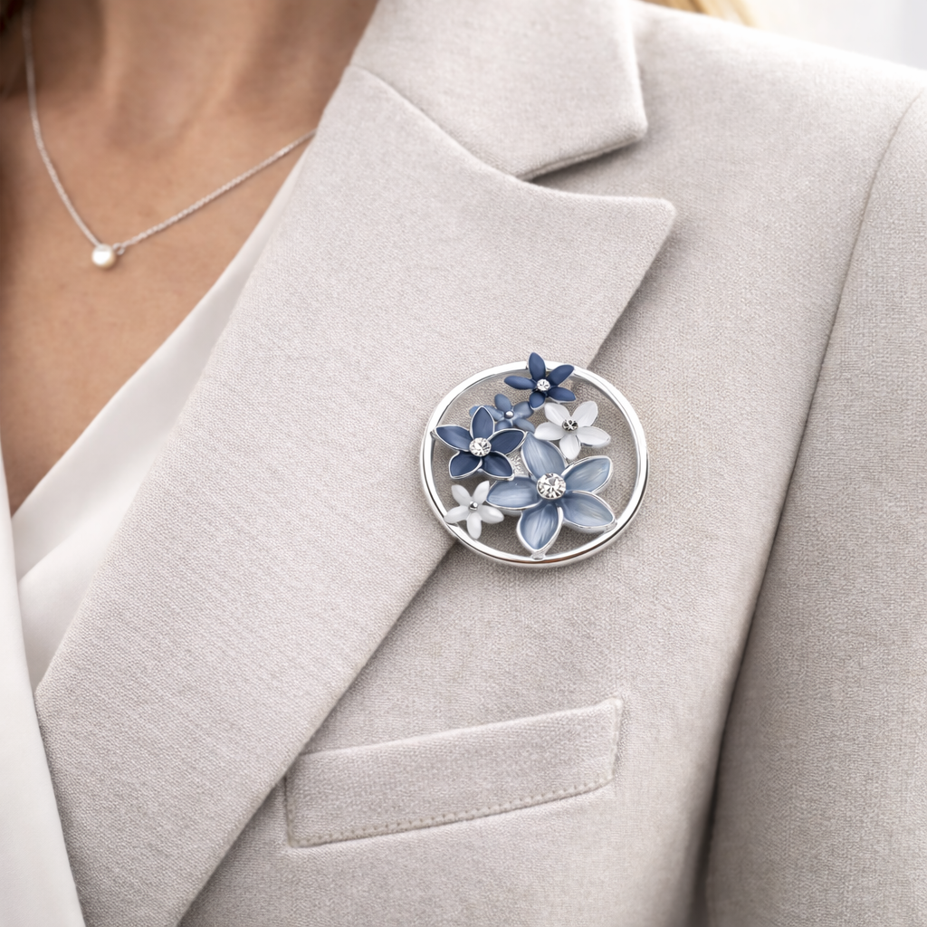 Magneetbroche Nr.37 Harmonie in Bloei gedragen op een licht colbert, elegante damesbroche met blauwe bloemen in een sierlijke cirkelvorm.