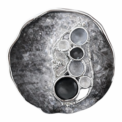 Magneetbroche Nr.42 Zwarte pracht met zwart- en grijstinten, ronde vormen en verfijnde zilverkleurige details.